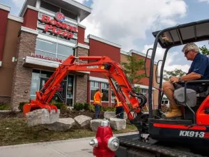 Excavator planting decorative rocks in front of Toronto business